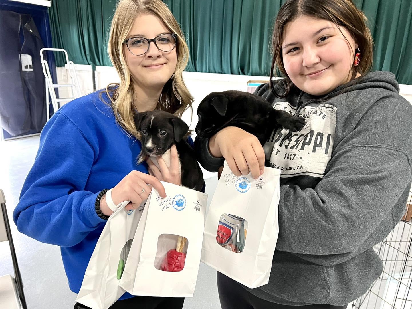 Two young IARN volunteers holding rescued puppies at a community event
