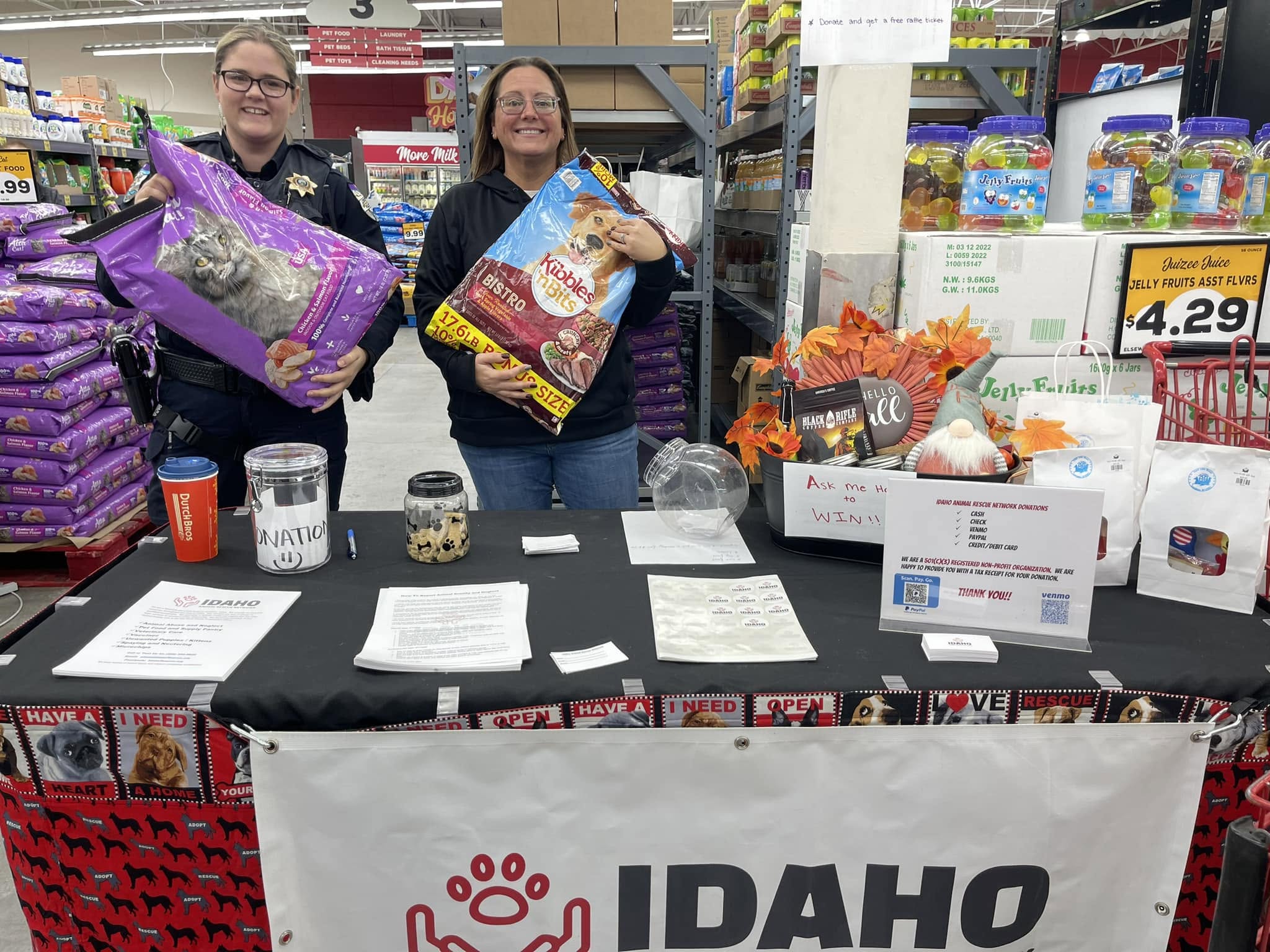 Two IARN volunteers holding dog-food bags at a community outreach table