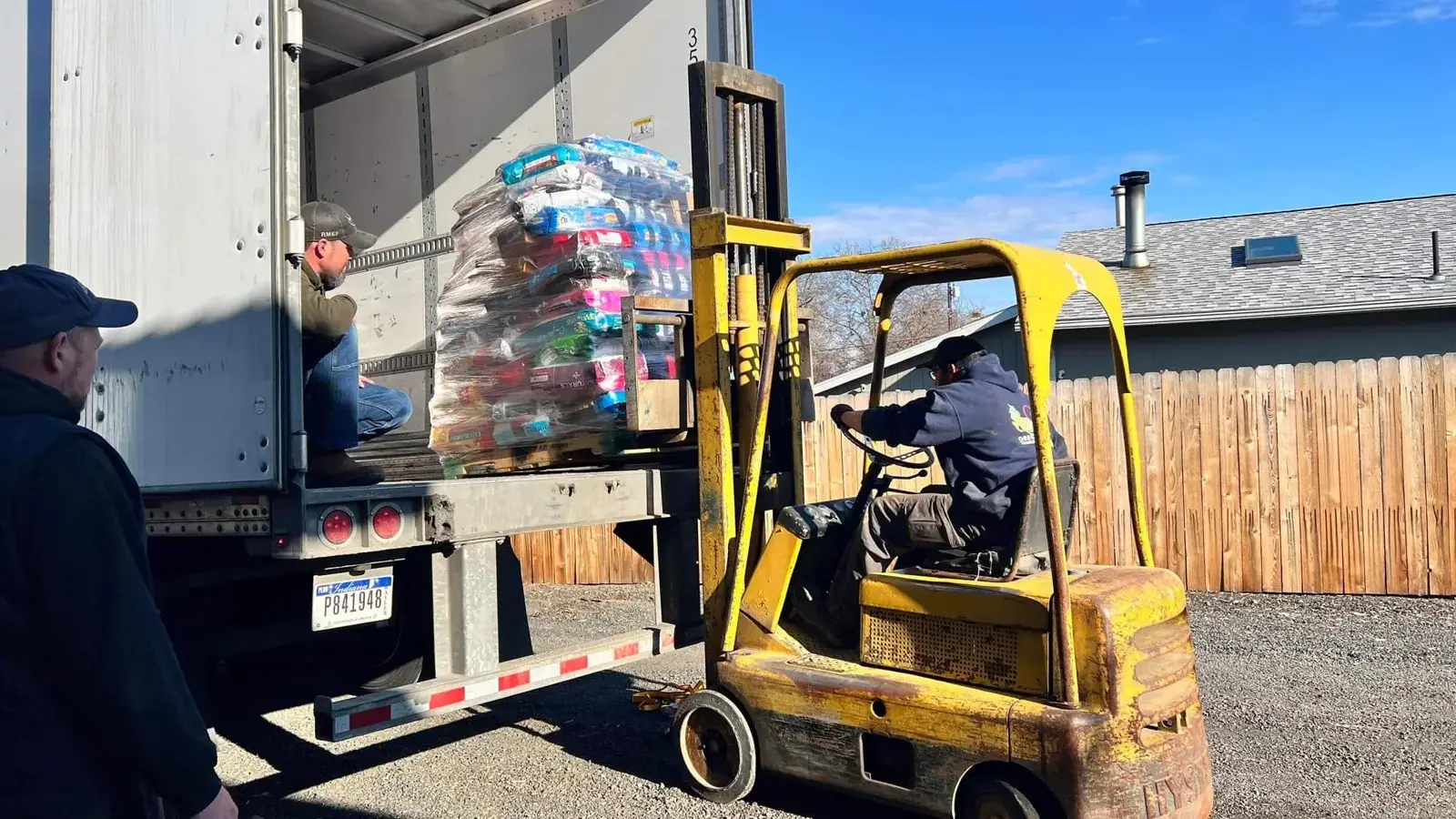 Volunteers unloading a pallet of donated pet food with a forklift